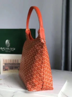 Goyard Hobo Boh è Me Stray Bag in orange, showcasing a stylish underarm design with a textured pattern, positioned next to a green branded box, emphasizing its trendy and casual aesthetic.