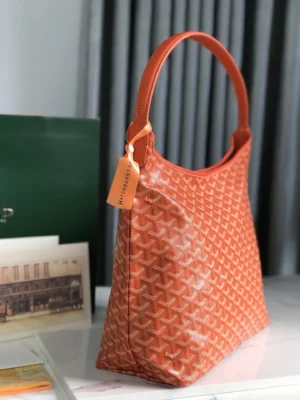 Goyard Hobo Boh è Me Stray Bag in orange, showcasing signature pattern and shoulder strap, positioned on a surface with a blurred background.