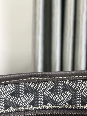 Close-up of Goyard Hobo Boh è Me Stray Bag featuring distinctive patterned fabric and stitching details, with a blurred background of vertical stripes.