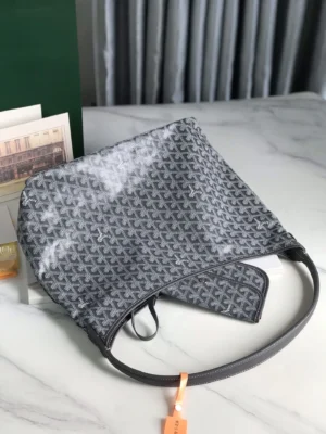 Goyard Hobo Boh è Me Stray Bag in gray, featuring a distinctive logo pattern and a comfortable shoulder strap, displayed on a marble surface with decorative items in the background.