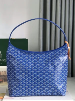 Goyard Hobo Boh è Me Stray Bag in blue with signature pattern, featuring a shoulder strap and zipper closure, displayed on a marble surface with blurred background elements.