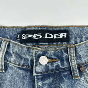 SP5DER logo on blue cowboy shorts waistband with button detail.