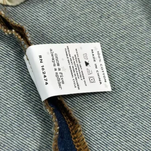 Label on SP5DER White Logo Blue Cowboy Shorts, featuring care instructions and fabric details.