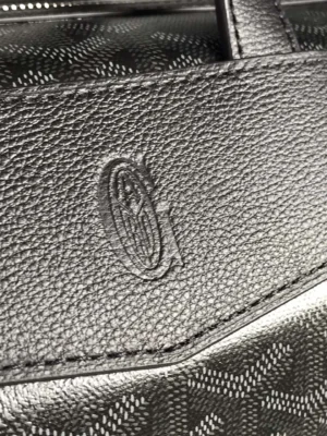 Goyard Cisalpin Backpack close-up showcasing embossed logo on leather and Goyardine canvas pattern, emphasizing luxury design and craftsmanship.