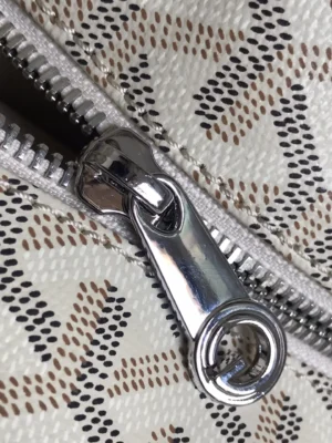 Close-up of a zipper on a Goyard White Tote Bag, showcasing the intricate patterned fabric and high-quality metal zipper detail.