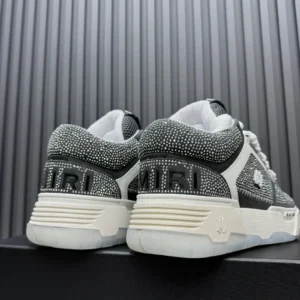 AMIRI Trainer sneakers featuring a sleek design with rhinestone detailing, showcasing the brand logo on the heel, set against a textured background.