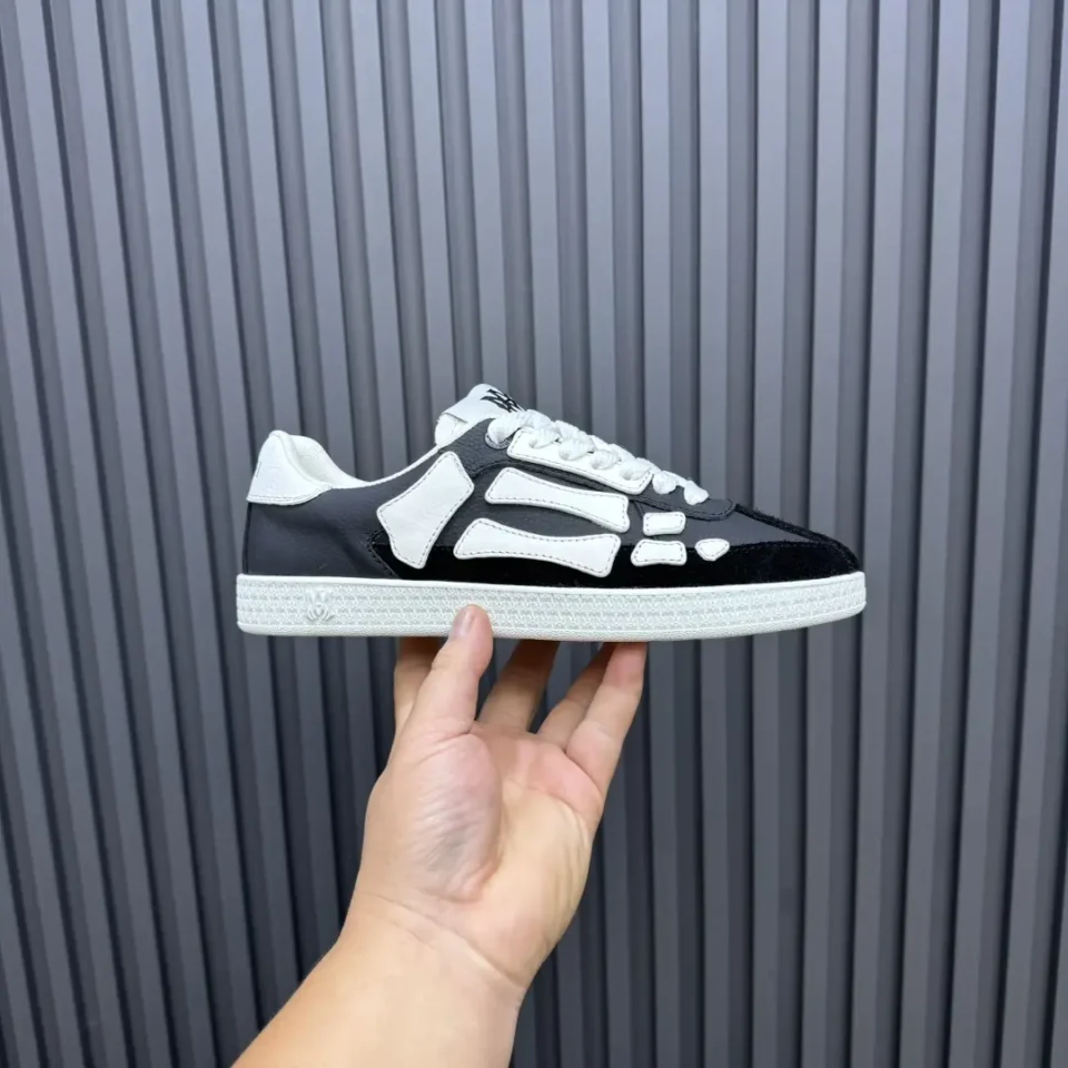 Veja V-10 black white skeleton design leather sneakers held against ribbed gray background