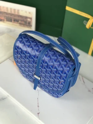 Goyard Belvedere 2nd Generation Bag in blue, featuring a textured pattern, adjustable shoulder strap, and minimalist design, displayed on a marble surface with a green background.