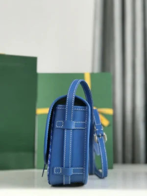 Blue Goyard Belvedere 2nd Generation Bag showcasing side view, featuring elegant design, leather material, and adjustable shoulder strap against green gift bags.