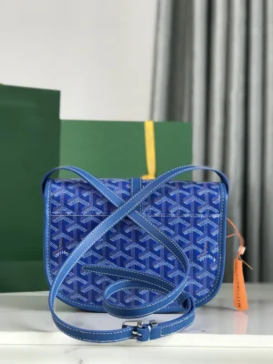 Goyard Belvedere 2nd Generation Bag in blue with adjustable shoulder strap, displayed on a marble surface with green packaging in the background.