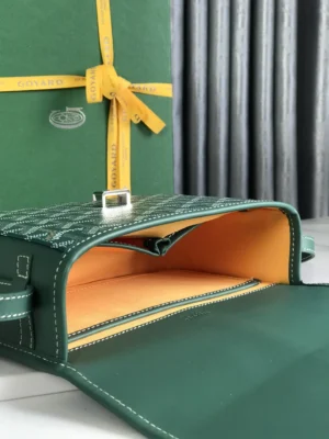 Green Goyard Belv é d è re 2 crossbody bag with silk ribbon, showcasing its interior and leather lining, against a backdrop of a branded box and fabric.