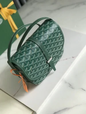 Green Goyard Belv é d è re 2 crossbody bag with silk ribbon, featuring a minimalist design and adjustable shoulder strap, displayed on a marble surface.