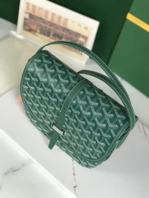Green Goyard Belv é d è re 2 crossbody bag with silk ribbon, featuring a woven pattern and adjustable strap, displayed on a marble surface.