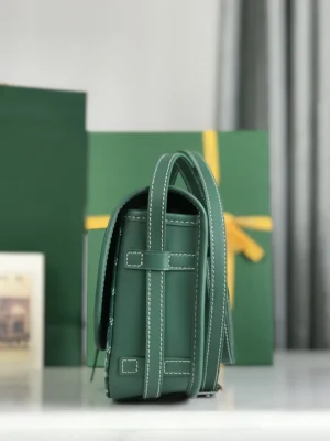 Green crossbody bag with silk ribbon detail, showcasing minimalist design and Goyard branding, against a backdrop of gift-wrapped boxes.