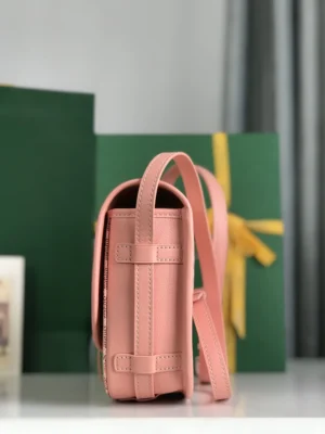 Metallic leather crossbody shoulder purse in pink, showcasing adjustable straps and minimalistic design, placed against a backdrop of green gift boxes.