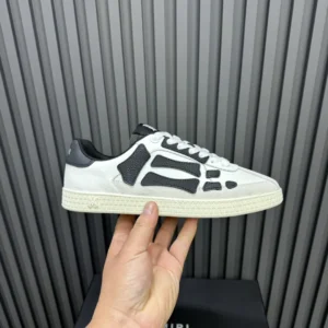 AMIRI Trainer sneakers featuring a unique black and white design, held in hand against a textured background, showcasing luxury footwear suitable for replica enthusiasts.