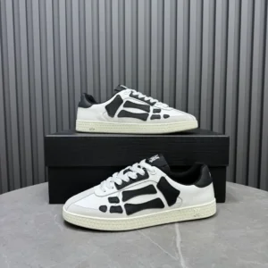 AMIRI Trainer sneakers featuring a white and black design, displayed on a black box against a textured gray background, highlighting luxury footwear for sale at 9.00.