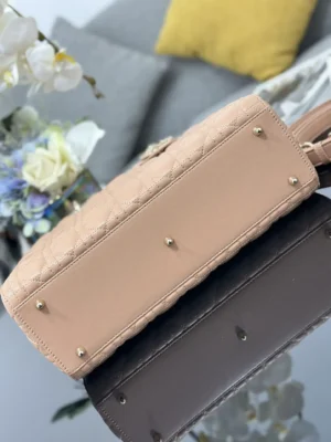 Dior Book Tote Bag showcasing refined leather, iconic wicker stitch, and gold accents, set on a reflective surface with floral decor in the background.