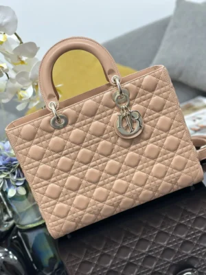 Dior Book Tote Bag in refined leather with iconic wicker stitch and light gold "D.I.O.R." pendant, featuring detachable straps and internal zipper pocket, displayed elegantly on a textured surface.