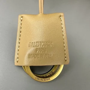 Balenciaga handbag tag featuring embossed logo, leather texture, and circular metal ring, highlighting designer craftsmanship and authenticity.