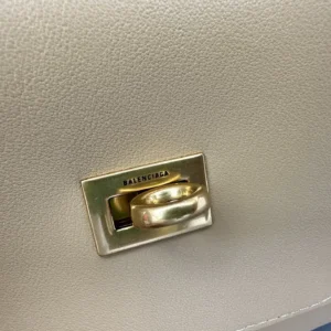 Close-up of Balenciaga handbag clasp featuring gold hardware and logo, showcasing the stylish design of the trending designer shoulder bag.