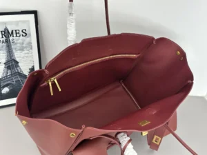 Interior view of a modern Balenciaga tote bag replica in burgundy, featuring a zippered pocket and leather straps, showcasing its stylish design and practical use.