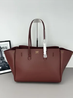 Modern City Tote Bag by Balenciaga, featuring a sleek design in burgundy with leather straps and front flip decoration, showcasing a blend of practicality and futuristic style.