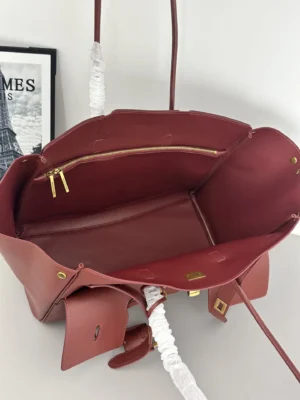 Interior view of a modern Balenciaga tote bag featuring a rich burgundy color, gold zipper accents, and a spacious design, showcasing its practical and stylish elements for fashion enthusiasts.