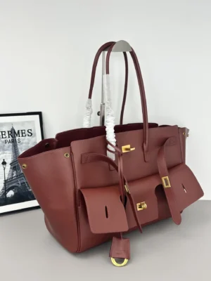 Modern City Tote Bag replica by Balenciaga in burgundy leather, featuring front flip decoration, square locks, and leather straps, set against a Paris-themed backdrop.