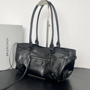 Black leather Balenciaga Le City Horizontal Motorcycle Bag with vintage hardware, displayed on a black surface alongside a branded box.