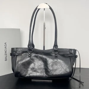 Vintage black leather Balenciaga Horizontal Motorcycle Bag with textured finish, stylish handles, and retro charm, displayed against a minimalist background.
