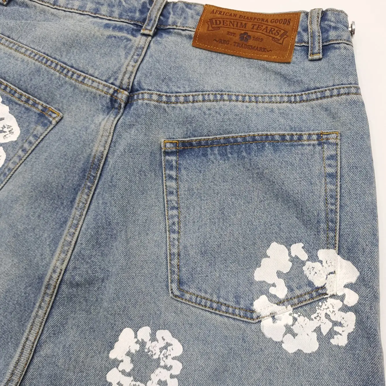 Denim Tears jeans light blue cotton denim with white floral prints and leather patch label