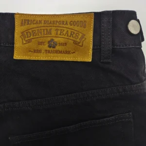 Denim Tears black denim jeans with brown leather patch African Diaspora Goods logo sturdy cotton material