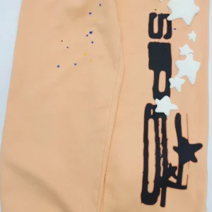 Sp5der Orange Pink Star Pants featuring star designs and colorful detailing on a peach background, showcasing unique fabric and print quality.