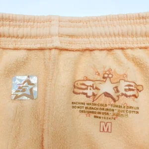 Sp5der Orange Pink Star Pants fabric tag showing care instructions and logo detail.