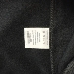 No brand, model, or product type visible; fabric label showing washing instructions and material composition on black cotton fabric
