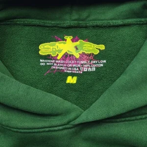 Sp5der Deep Green Bead Hoodie tag featuring care instructions and size label, showcasing vibrant yellow logo and design details.