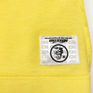 Hellstar Yellow Marathon Short Sleeve shirt close-up, featuring logo tag and vibrant yellow fabric, highlighting quality materials and design.