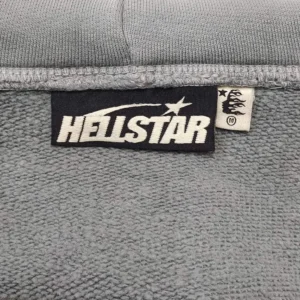 Hellstar clothing tag black and white logo on gray fabric medium size label with flame design