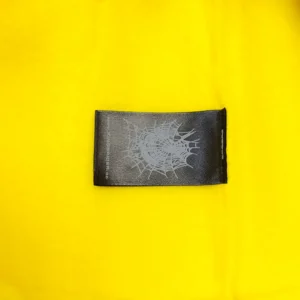 Off-White textile label black with silver spider web print on yellow fabric background