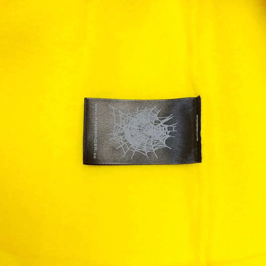 Off-White textile label black with silver spider web print on yellow fabric background
