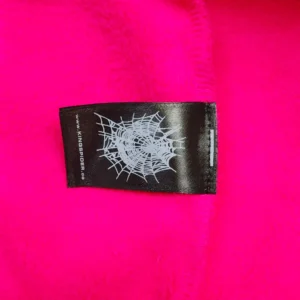 Label tag on bright pink hoodie featuring spider web design, associated with SDER Rose Red Hot Diamond White Word Legacy Hoodie.