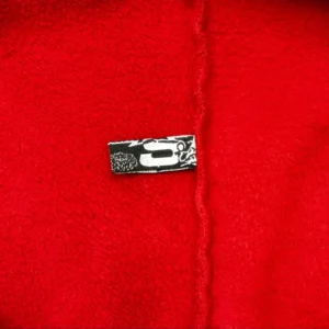 Supreme fleece fabric red soft textured material close-up with stitched edge and black white label
