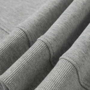 Close-up of the fabric texture and cuffs of a gray hoodie from the Denim Tears Cotton Flower collection, highlighting high-quality materials and design details.