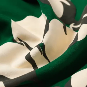 Close-up of green fabric featuring a floral design, highlighting the texture and detail of the Denim Tears Cotton Flower hoodie.