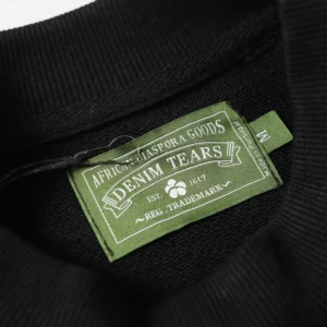 Denim Tears clothing label showcasing brand name and trademark details on a black hoodie.