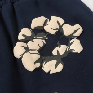 Cotton flower graphic design on Denim Tears shorts, showcasing trendy streetwear style in navy background.