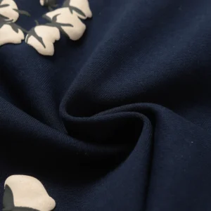 Close-up of Denim Tears Cotton Flowers printed fabric, featuring floral design on navy background, highlighting texture and detail for trendy streetwear shorts.