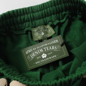 Denim Tears brand tag on green shorts featuring African Diaspora Goods label, showcasing trendy streetwear design and premium quality.