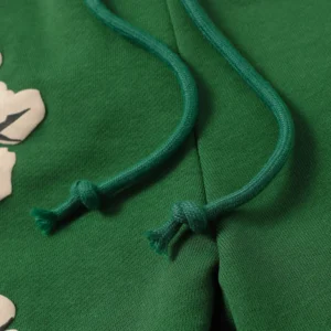 Green shorts featuring cotton flowers design and matching drawstrings, part of Denim Tears collection.